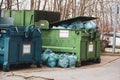 Next to 2 trash compactors are numerous blue trash bags