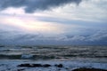 Next view of the churning sea in the evening with dark menacing clouds and the sun setting as background