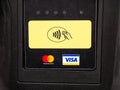 NFC card EMV contactless payment symbol on a payment terminal near MasterCard and Visa bank logos, object front view, closeup,