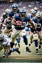 an NFL running back breaking through the defensive line and sprinting towards the end zone, leaving a trail of defenders in his