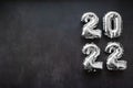 Nflatable shiny silver numbers of the new year 2022 on a dark grey or black background. Copy space Royalty Free Stock Photo