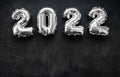 Nflatable shiny silver numbers of the new year 2022 on a dark grey or black background. Copy space Royalty Free Stock Photo
