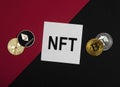 NFT acronym on paper note on red and black background with cryptocurrency coins