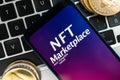 NFT cryptoart marketplace concept. Mobile phone for working with non-fungible token and ethereum coin on laptop keyboard