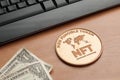 Nft non fungible token concept: big copper coin on a wooden table with a computer keyboard and two dollar bills
