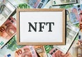 NFT non-fungible token text. Concept words NFT non-fungible token on paper blank. Background of euro bills. Blockchain