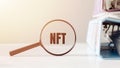 NFT - non-fungible token - is word on magnifier in office