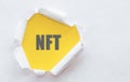 NFT text written under torn paper on yellow background Royalty Free Stock Photo