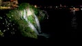 Nght Waterfall with Beautiful Lighting Flowing into Sea from Great Height of Steep Shore, against Background of Night