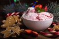 Ice cream served in a glass bowl. Displayed with candy canes on wooden rustic table. Sparkling Christmas tree lights background