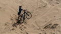 Girl with a bicycle climb the sand dunes