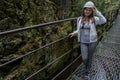 Girl in a working helmet is in the rocks near the waterfall