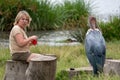 A Marabou Stork bird (defocused), harrasses a woman tourists while she is drinking a