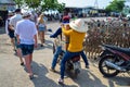 NHA TRANG, VIETNAM - APRIL 19, 2019: People in hats carry boxes on a motorcycle and tourists in Asia