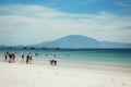 people relax on the beach and swim in the sea during the day. mountains in the background. Locals