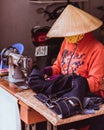 Nha Trang, Vietnam: a tailor works with jeans at the table with an old sewing machine Royalty Free Stock Photo