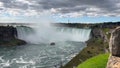 A boat with tourists is driving close to the famous `The Horseshoe Falls` and partly disappears in the spume