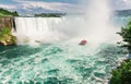 gorgeous view of Niagara Falls with passenger boat tourists, people floating, going toward the Falls at sunset time