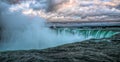 Niagara Falls mid day with a cloudy sky and misty overhead.