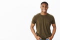 Nice african american guy smiling at camera while standing in casual pose in hucky t-shirt with hands in pockets looking