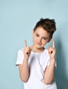 Nice amiable little boy in white t-shirt looking forward with smile putting both index fingers up.