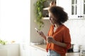 Nice App. Smiling Black Woman Using Smartphone And Drinking Tea In Kitchen Royalty Free Stock Photo