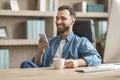 Nice App. Young Businessman Relaxing With Smartphone And Coffee At Workplace Royalty Free Stock Photo