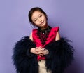 Nice asian korean kid girl lady in stylish fur coat and pink t-shirt is posing with her head tilted slightly to the side