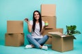 Nice attractive cheery girl sitting in lotus pose with pile stack boxes holding in hands house figure keys realestate