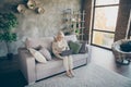 Nice attractive focused concentrated gray-haired blond middle aged granny sitting on divan resting using laptop calling