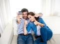 Nice attractive young couple sitting together in sofa couch taking selfie photo with mobile phone Royalty Free Stock Photo