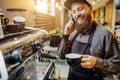 Nice bearded barista stands at coffee machine and talks on phone. He smiles. Guy hold cup of coffee in hands.