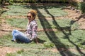 Nice beautiful middle age lady sitting on a timo grass enjoying the nature in outdoor leisure activity, summer and sunny day