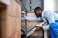 Nice Black Handyman in Blue Overalls Uniform Is Going To Repair Dishwasher