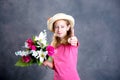 Nice blond girl with straw hat, bouquet of flowers and thumb up