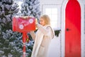 Nice blonde curly girl with letter near the Santa`s mailbox