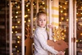 Nice blonde girl on the new year carousel with wooden deer and bright lights