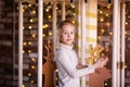 Nice blonde girl on the new year carousel with wooden deer and bright lights