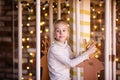 Nice blonde girl on the new year carousel with wooden deer and bright lights