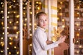 Nice blonde girl on the new year carousel with wooden deer and bright lights