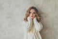 Nice blonde woman with healthy curly hair on gray background portrait