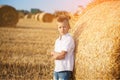 The nice boy in the field of near stack of straw at sunset