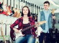 Nice boy and girl teenagers examining electric guitars