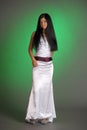 Brunette girl in a long white dress in the studio on a green background Royalty Free Stock Photo
