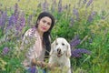 nice brunette girl posing with golden retriver at blooming Lupins meadow at country side. cloudy evening