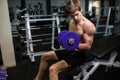 Nice burn in bicep. Side view of confident young handsome man in sportswear exercising with dumbbell at gym Royalty Free Stock Photo