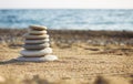 Zen pyramid of spa stones on the blurred sea background. Sand on a beach. Sea shores. Water waves texture. Left side of photo. Pla