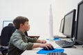 Nice caucasian concentrated boy using computer and the computer mouse