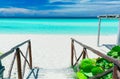 Nice charming view of tropical white sand beach and inviting tranquil, turquoise ocean on blue sky background
