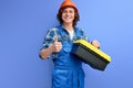 nice cheerful qualified workman in overalls carrying instruments isolated over purple background